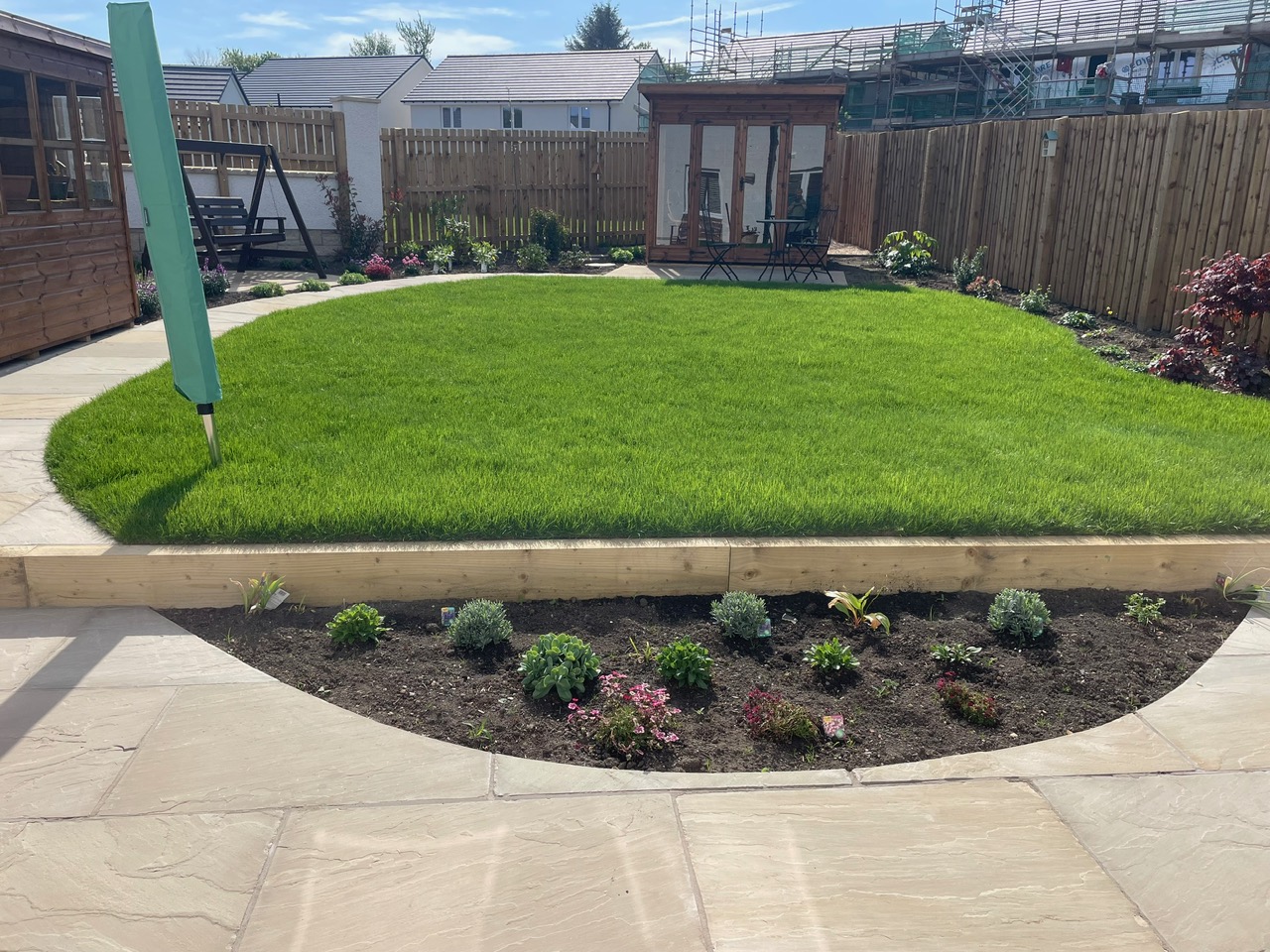 New back garden with sandstone patio, oval lawn, sleeper border and summerhouse - Edinburgh