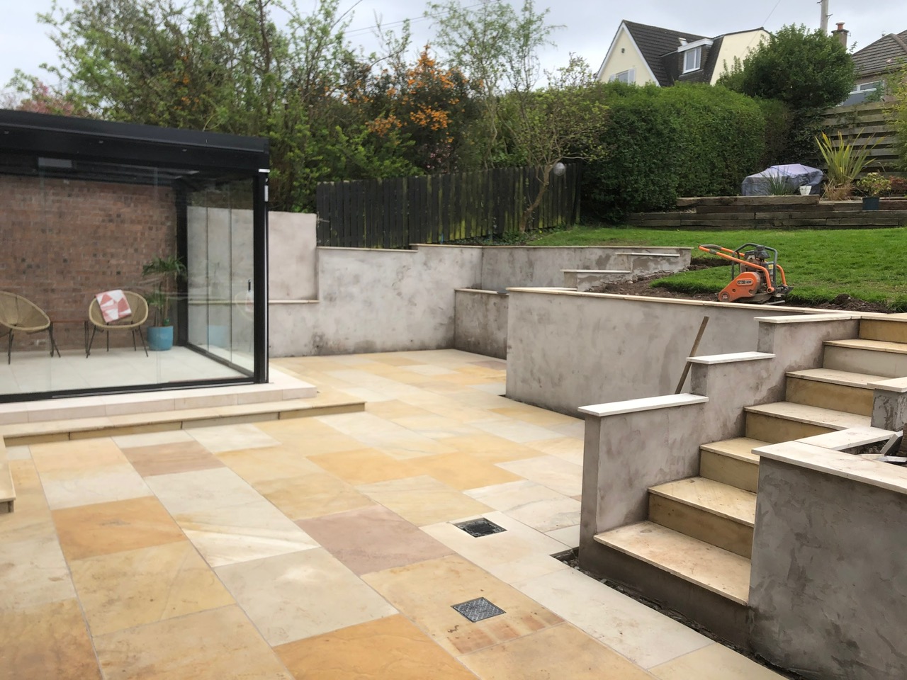 Sandstone patio with rendered retaining walls, garden room and bifold doors - Edinburgh