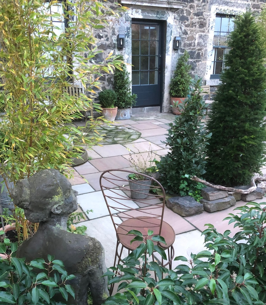 Stone cottage courtyard garden with sandstone paving, topiary and sculpture - Edinburgh